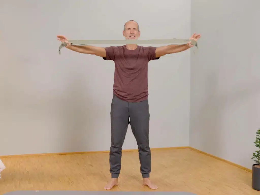 Roland Liebscher-Bracht hat die Arme zu beiden Seiten ausgestreckt und hält in seinen Händen ein hellgrünes Trainingsband.