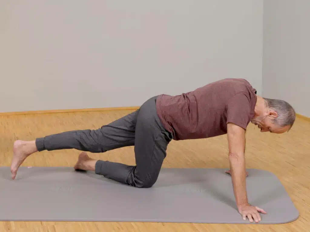 Roland Liebscher-Bracht kniet mit einem Bein am Boden, stützt seinen Oberkörper mit beiden Händen ab und streckt das andere Bein gerade nach hinten aus.