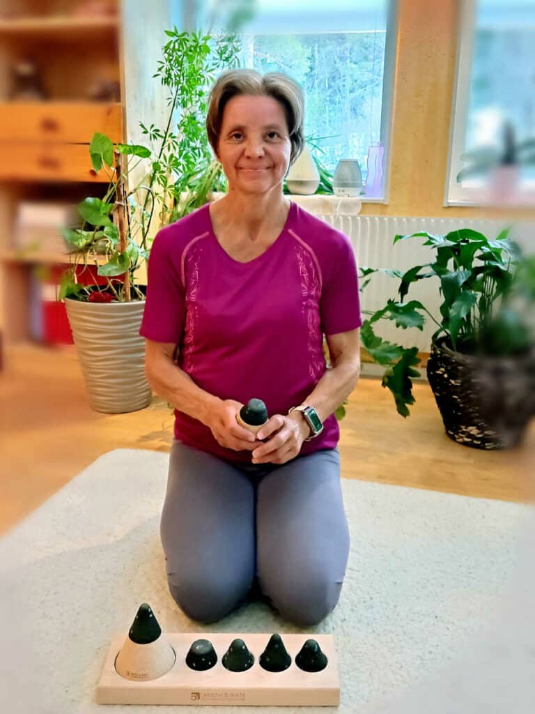 Eine Person sitzt im Fersensitz am Boden. Vor ihr ist das Drücker-Set von Liebscher & Bracht.