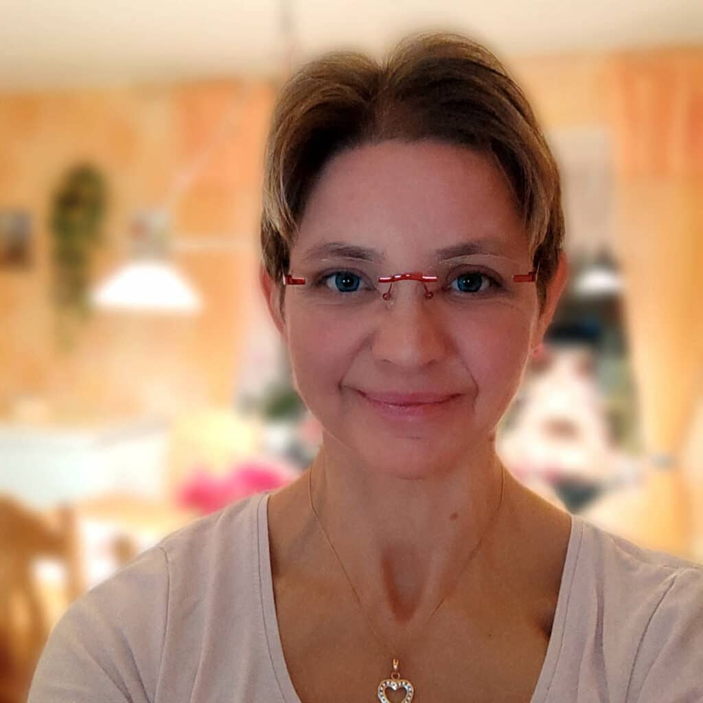 Eine Person lächelt in die Kamera. Sie trägt eine Brille und hat kurze Haare.