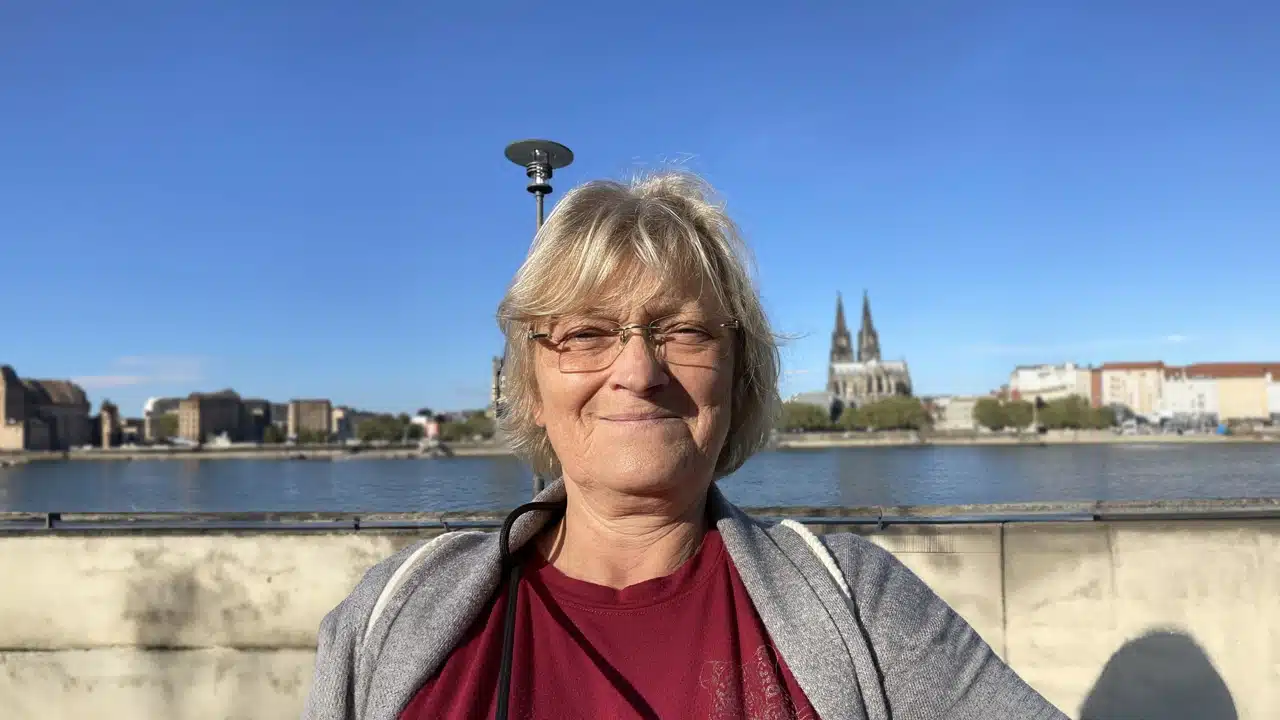 Gudrun steht vor einem blauen Himmel und lächelt in die Kamera.