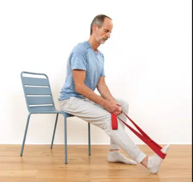 Nimm dir für diese Hallux Valgus Übung eine Dehnungsschleife und setz dich auf einen Stuhl.